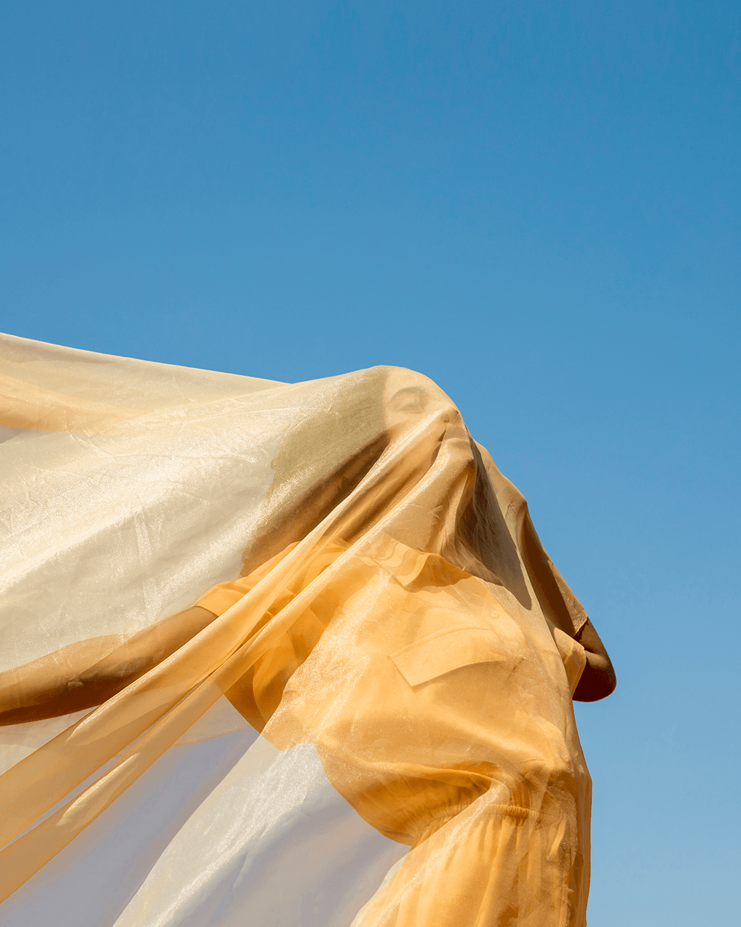 Frau hinter fließendem, weißem transparentem Stoff