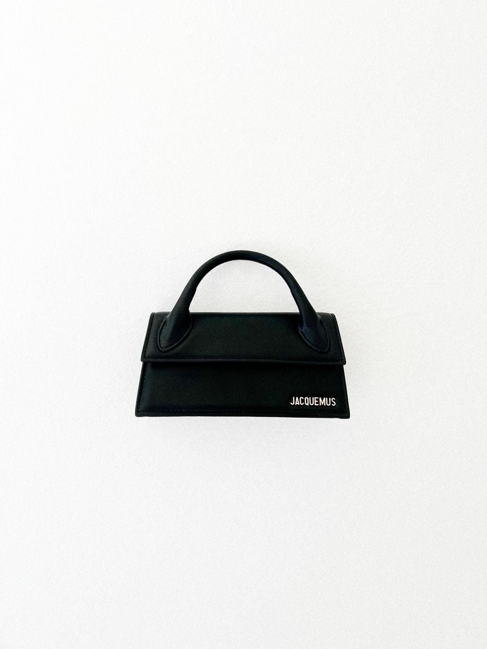Black structured handbag photographed against a light background