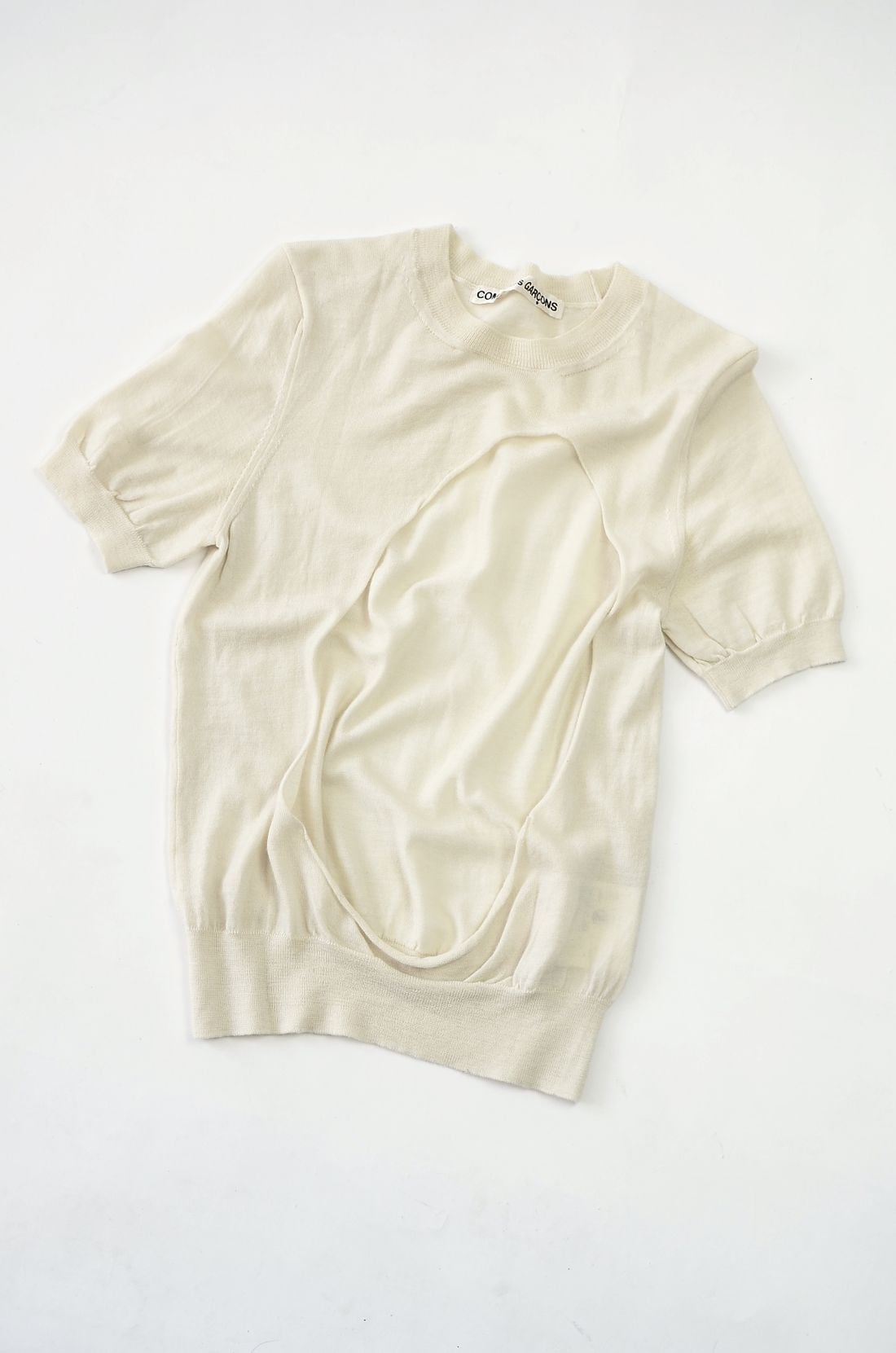 Cream knit garment photographed flat on a neutral background