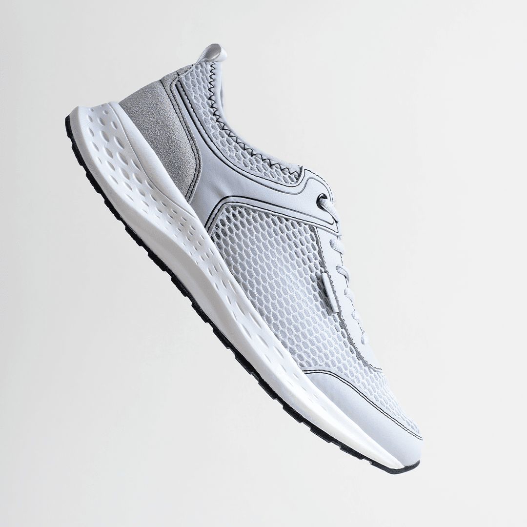Light gray mesh running shoe floating against a soft gray background