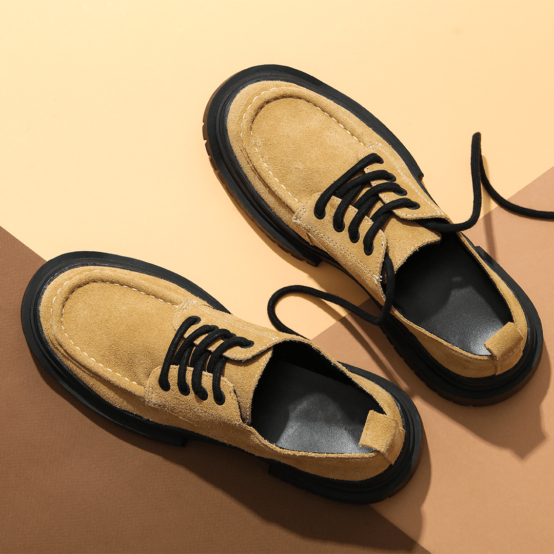 Pair of tan suede lace-up shoes arranged on a two-tone tan background